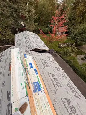 Roof deck covered in synthetic underlayment with shingle bundles staged